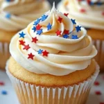 All-American Vanilla Cupcakes: Easy & Festive 4th of July Recipe 7 All-American Vanilla Cupcakes topped with creamy vanilla buttercream frosting and decorated with red and blue star-shaped sprinkles on a white plate with a soft gray linen background.