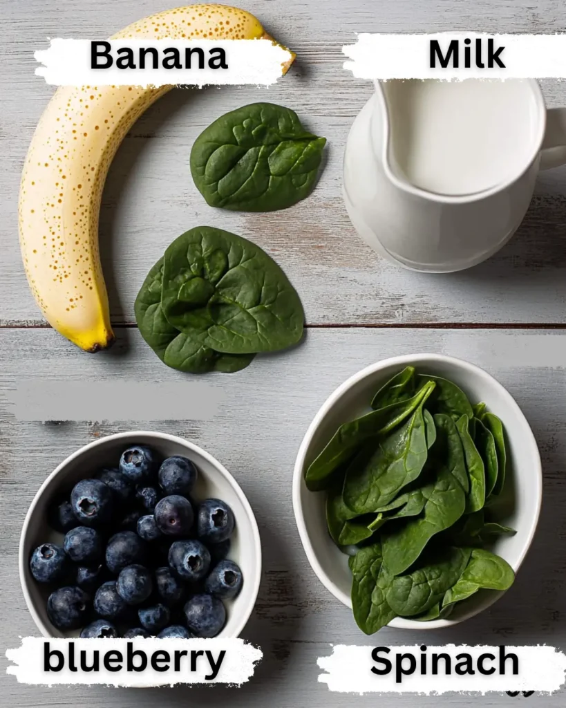 Flat lay of berry banana spinach smoothie ingredients labeled on white tile—banana, yogurt, spinach, milk, and blueberries.