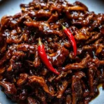 Crispy Chilli Beef Recipe: Perfect Sweet & Spicy Crunch 5 Crispy chilli beef with red chillies on a blue plate – sticky, golden, and garnished to perfection