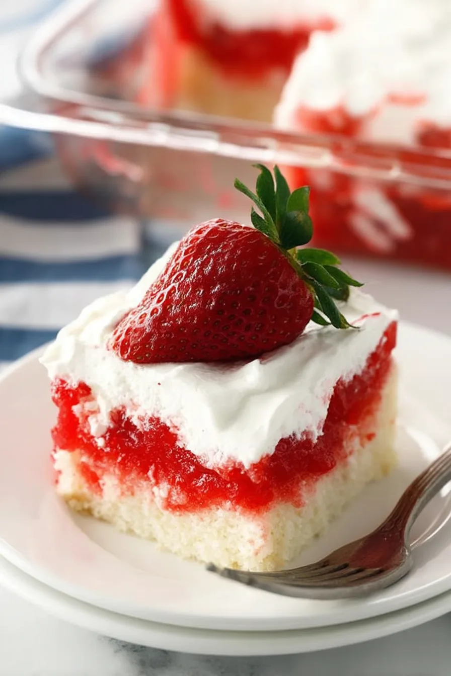 Slice of strawberry Jello poke cake with Cool Whip topping and fresh strawberry garnish on a white plate.