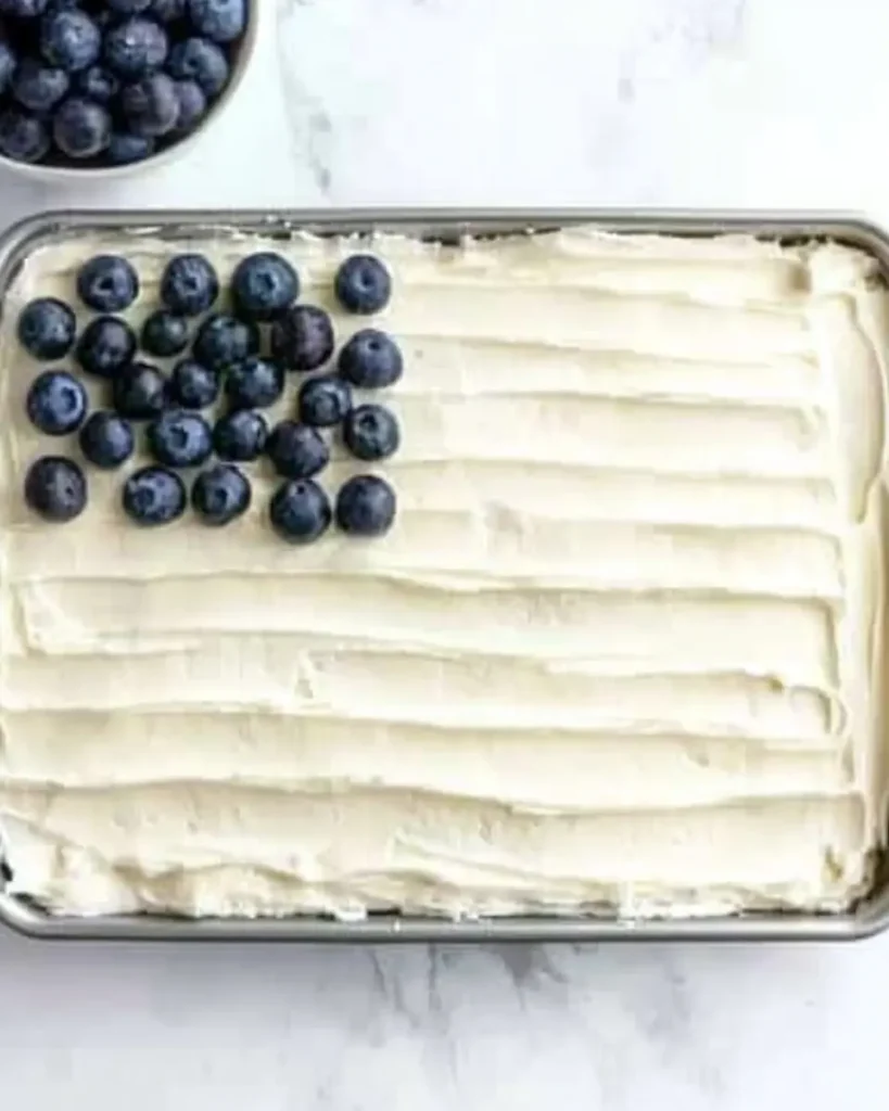 Flag Cake Recipe: Easy Strawberry Jello Dessert for July 4th 7 Sheet cake with whipped topping and blueberries in the top-left corner for American flag decoration.
