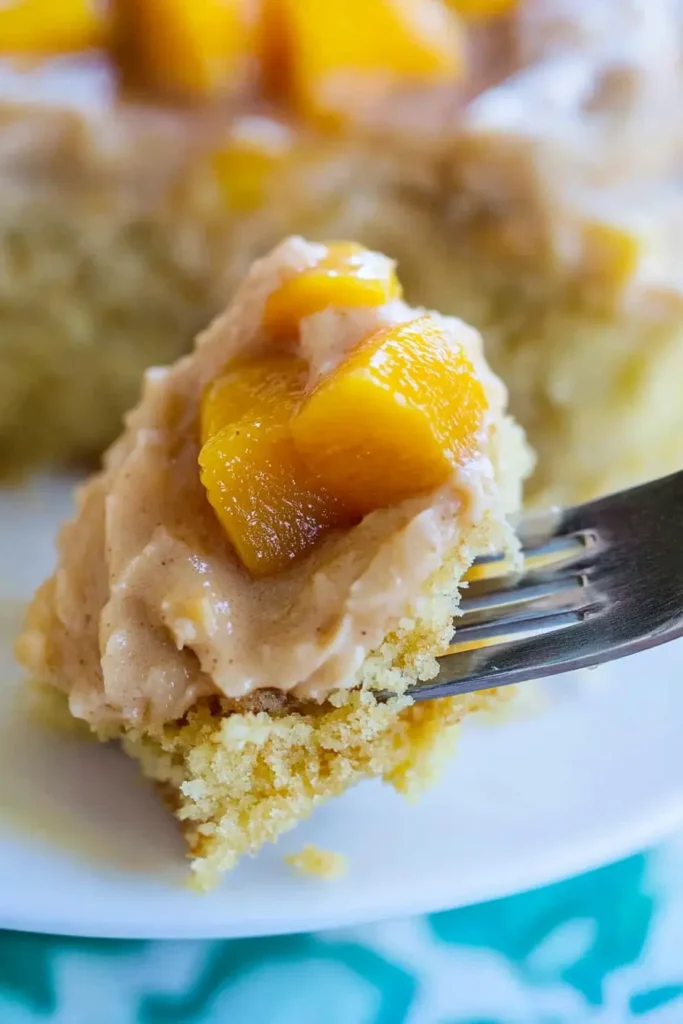 Peach Cake with Brown Sugar Frosting: A Moist, Dreamy Dessert 4 Fork lifting a moist bite of peach cake with brown sugar frosting and peach chunks