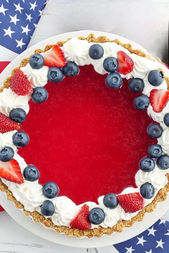 4th of July Patriotic Jello Pie: A No-Bake Red, White & Blue Treat 6 Top-down view of 4th of July Patriotic Jello Pie with whipped cream, fresh blueberries and strawberries on a graham cracker crust.