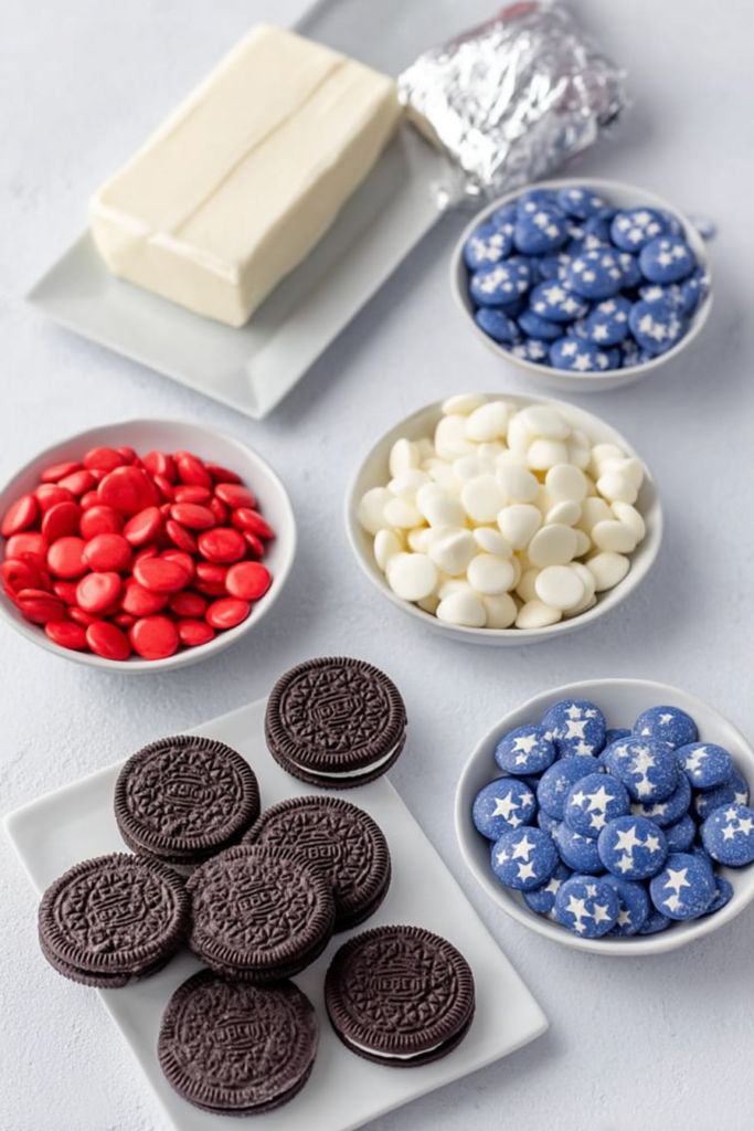 Overhead flat lay of Oreo truffle ingredients including cookies, red and blue candy melts, white chocolate chips, sprinkles, and cream cheese.