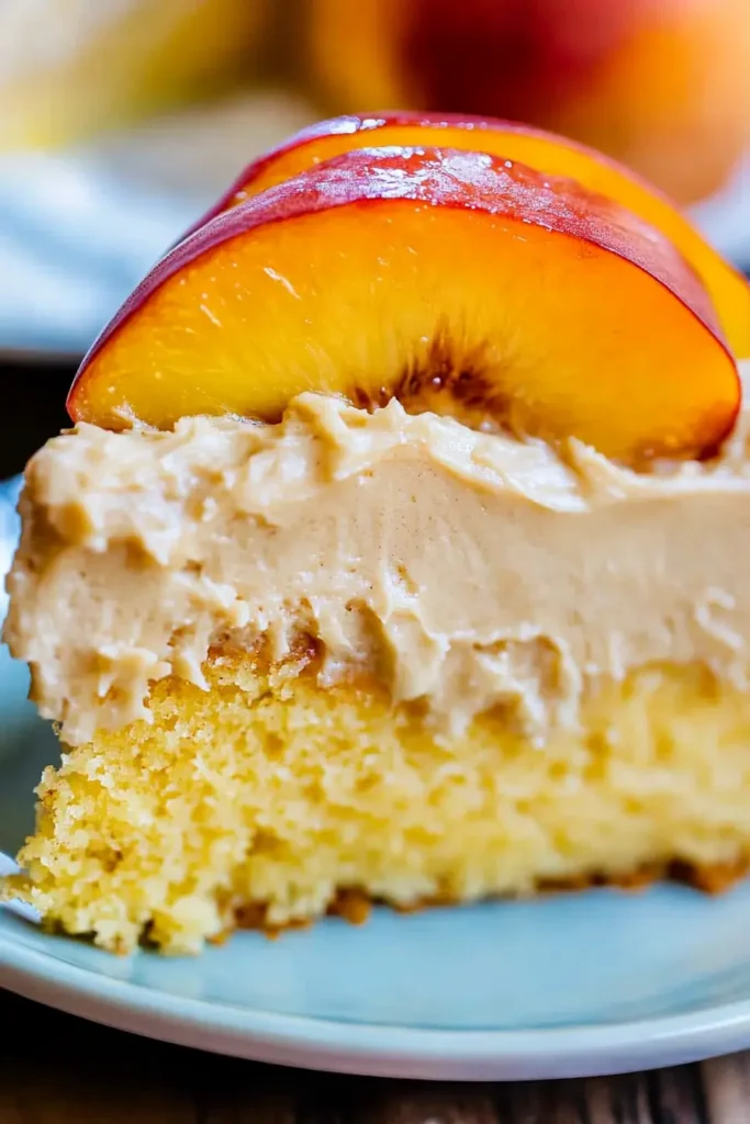 Close-up of a moist peach cake slice topped with brown sugar frosting and peach slices