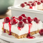 Cherry Delight: The Best No-Bake Summer Dessert 11 Cherry Delight dessert slice with graham cracker crust, creamy filling, and cherry topping on a plate
