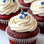 Red Velvet Cupcakes With Cream Cheese Frosting for 4th of July 9 three moist red velvet cupcakes topped with creamy smooth cream cheese frosting and blue star sprinkles, on a white ceramic plate with a soft beige fabric background.