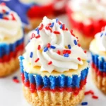 Red White and Blue Mini Cheesecakes – A Patriotic Dessert to Savor! 7 Red, white, and blue mini cheesecakes topped with whipped cream and patriotic sprinkles on a rustic tray