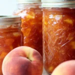 Spiced Peach Jam Recipe: Sweet, Easy & Full of Fall Flavor 5 Homemade spiced peach jam in mason jars with ripe peaches on a rustic table