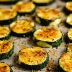 Baked Parmesan Zucchini: Crispy, Cheesy, and So Easy 6 Crispy baked zucchini slices topped with golden-browned parmesan cheese, roasted on a ceramic tray with black pepper and herbs