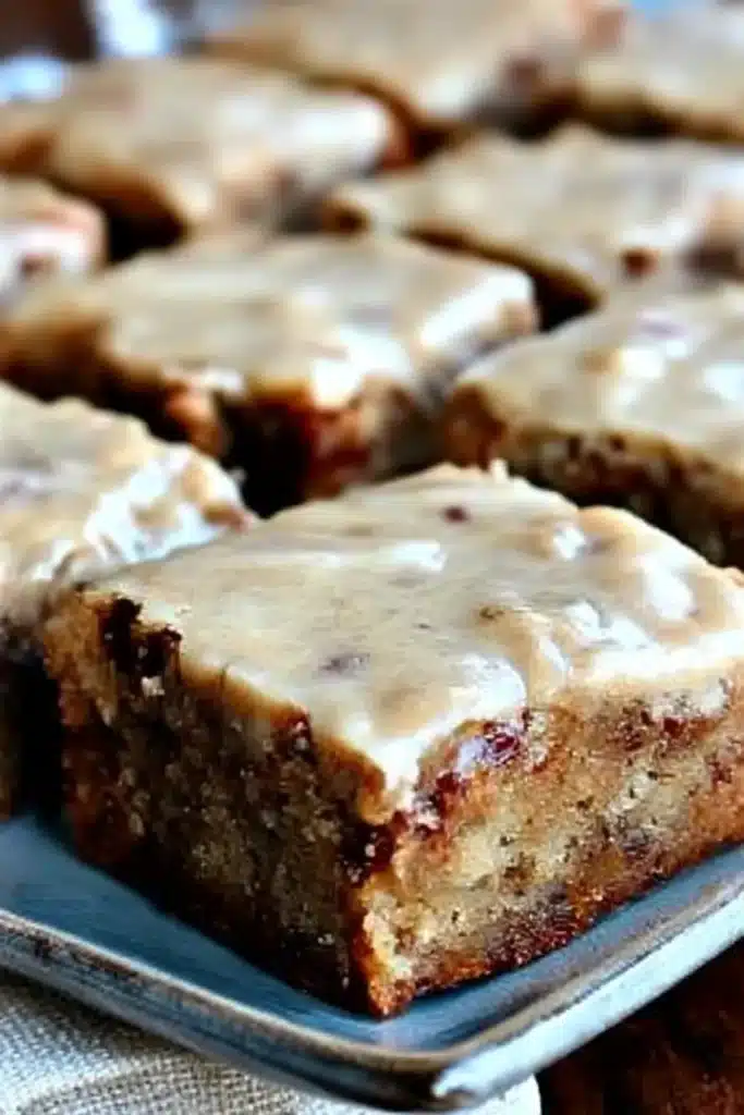 Moist banana bread brownies topped with brown butter frosting on a ceramic plate