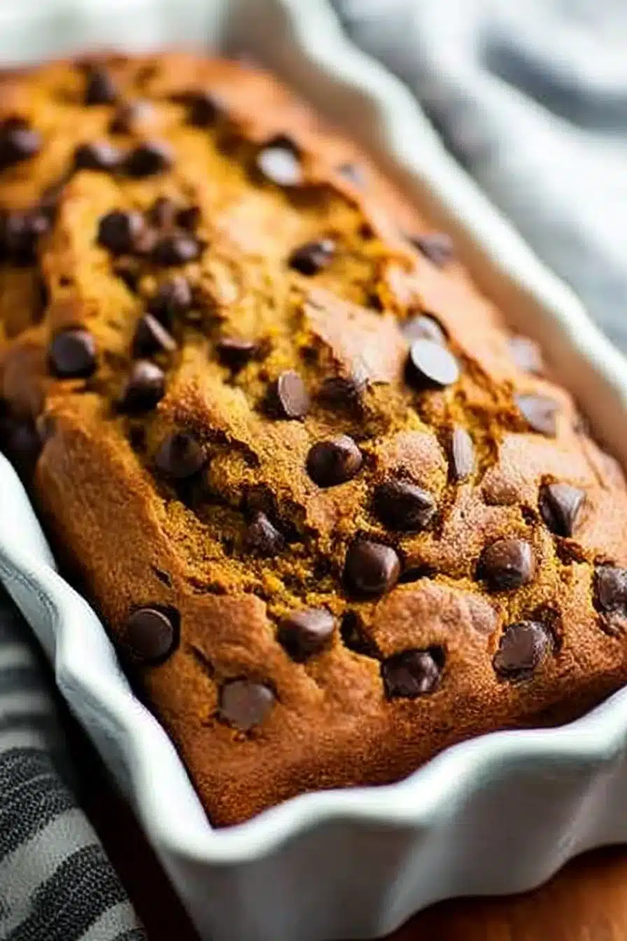Moist chocolate chip pumpkin bread with melted chips in a ceramic loaf pan