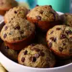 Chocolate Chip Zucchini Muffins – Moist & Easy Recipe 9 Homemade chocolate chip zucchini muffins in a white bowl with visible chocolate chips and zucchini flecks