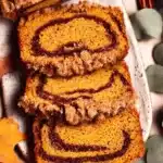 Cinnamon Swirl Pumpkin Bread: Moist, Spiced & Perfect for Fall 7 Moist cinnamon swirl pumpkin bread slices with pecan streusel topping on a rustic autumn background