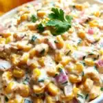 Creamy Corn Salsa – Easy, Crowd-Pleasing & Delicious Dip 9 Close-up of creamy corn salsa with corn, peppers, onions, and cilantro in a white bowl, served with chips.