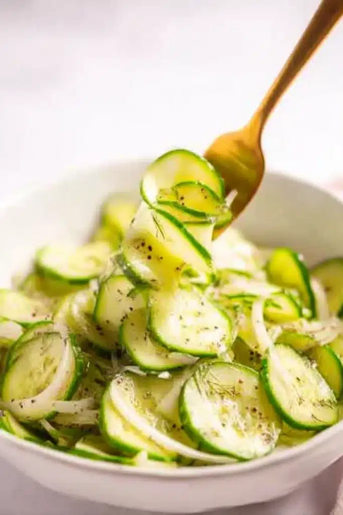 Cucumber Vinegar Salad – Simple, Tangy & Refreshing Favorite 8 Close-up of cucumber vinegar salad in a bowl with gold fork lifting cucumber slices.