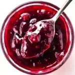 Cherry Syrup Recipe: Sweet, Simple & Ready in 15 Minutes 5 Thick homemade cherry syrup in a glass bowl with spoon – glossy, rich texture with real cherry chunks, perfect for pancakes or desserts.