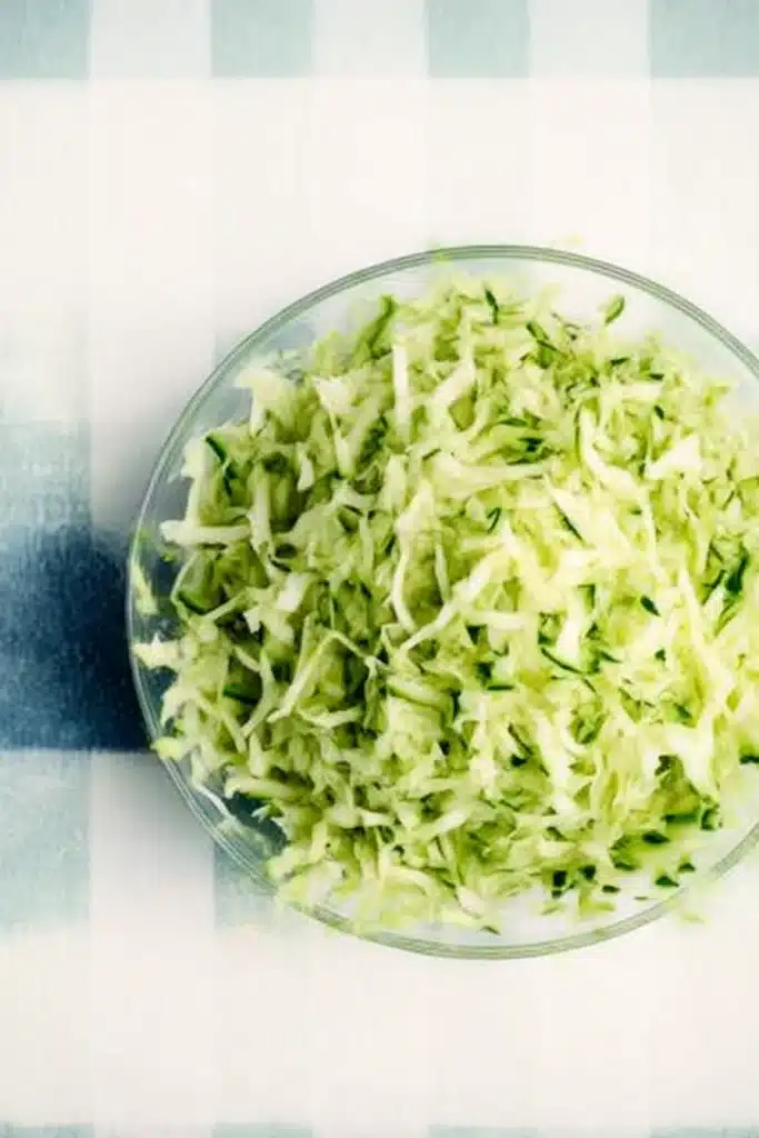 Zucchini Garlic Bites: Crispy, Cheesy & Perfect for Summer Snacks 5 Shredded zucchini in a large glass bowl ready for garlic bites preparation