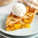 The Best Peach Pie – Gooey, Golden, and Packed with Flavor 9 A slice of the best peach pie with golden crust, gooey peach filling, and vanilla ice cream on a white plate