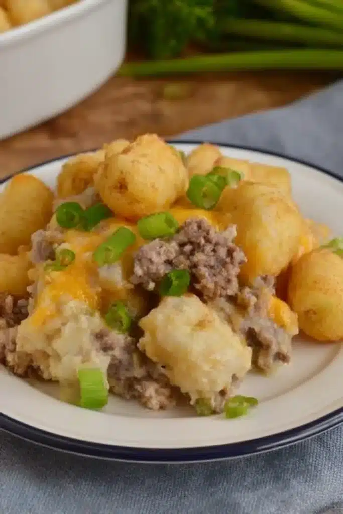 Slow Cooker Cowboy Casserole topped with golden tater tots, creamy ground beef filling, melted cheese, and green onions.
