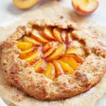 Peach Galette Recipe – A Rustic and Easy Summer Dessert 5 Rustic peach galette with golden flaky crust and juicy peach filling on parchment paper