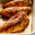 Baked Chicken Breasts – Juicy, Easy & Perfect Every Time 15 Golden baked chicken breasts with crispy seasoning in a white baking dish, resting in flavorful juices.