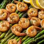 Lemon Garlic Shrimp and Asparagus: Easy One-Pan Dinner 6 Golden seared shrimp with fresh asparagus and lemon slices in a skillet, garnished with herbs and olive oil.