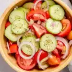 Fresh marinated cucumber tomato and onion salad in a ceramic bowl with herbs