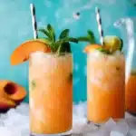 Pineapple Peach Agua Fresca: Easy, Refreshing Summer Drink 12 Two glasses of pineapple peach agua fresca over crushed ice, garnished with peach, lime, and mint on a chilled summer table.