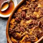 Close-up of pumpkin French toast casserole with pecan streusel in a rustic dish, served with maple syrup.