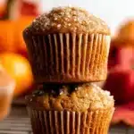 Easy Pumpkin Muffins – Super Moist One-Bowl Fall Recipe 12 Stacked easy pumpkin muffins with coarse sugar topping on a cooling rack, golden and moist with fall-inspired background