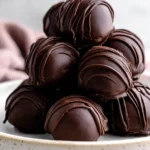 Peanut Butter Balls Recipe: Easy No-Bake Cream Cheese Treat 6 Stacked chocolate peanut butter balls with smooth coating and chocolate drizzle on a ceramic plate