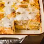 Biscuits and Gravy Breakfast Casserole | Easy & Delicious 3 Southern-style biscuits and gravy breakfast casserole in a ceramic dish, topped with creamy sausage gravy and melted cheese