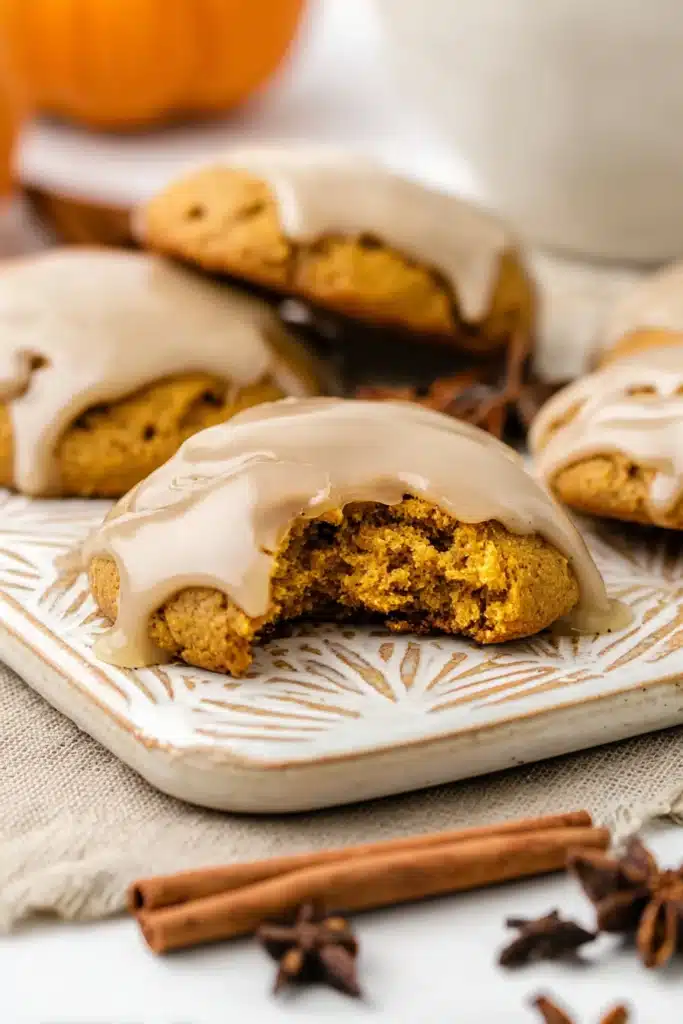 Pumpkin Cookies with Maple Glaze | Simple & Delicious 9 Close-up of a maple-glazed pumpkin cookie with a bite taken out, showing a soft and fluffy inside.