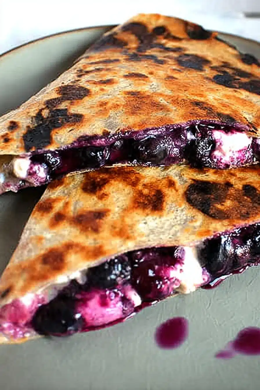 Crispy blueberry breakfast quesadilla with creamy cheese and juicy berries on a plate