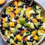 Blueberry Peach Feta Salad with fresh cucumbers, basil, and lemon vinaigrette in a rustic bowl