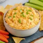 Buffalo Chicken Dip in a Crock Pot | Comforting & Easy 8 Buffalo Chicken Dip in a Crock Pot served in bowl with tortilla chips, celery, carrots, and sliced green onions