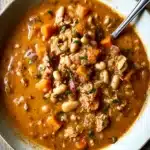 Chicken Chili with Pumpkin Recipe 7 Bowl of hearty chicken chili with pumpkin, carrots, and white beans on rustic wood table