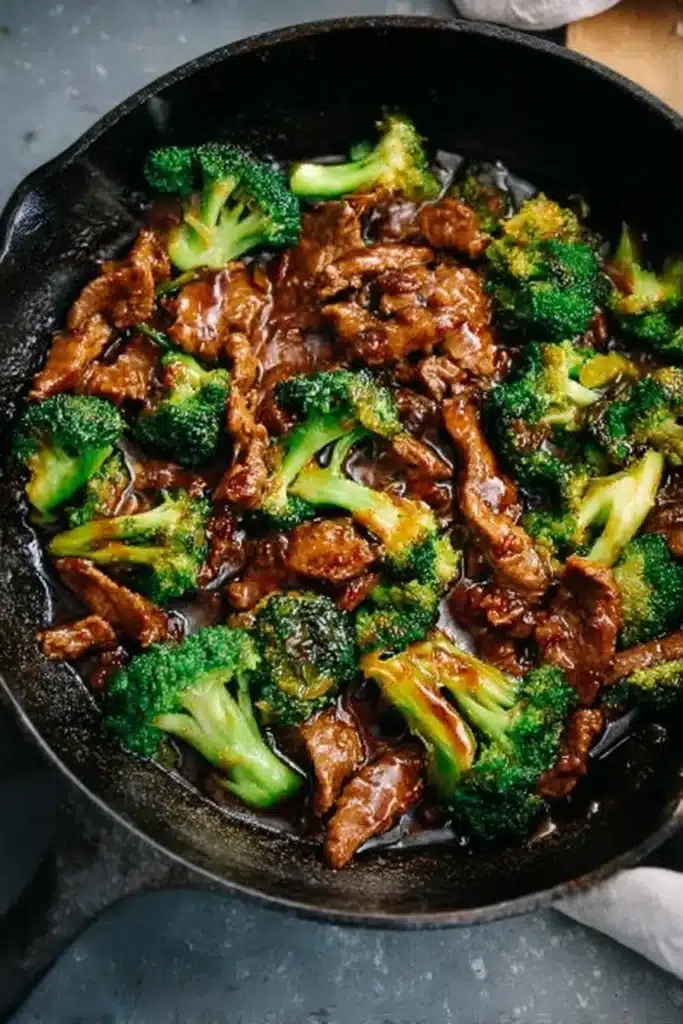 Chinese beef and broccoli stir-fry in thick garlic soy sauce, served in skillet over stone surface
