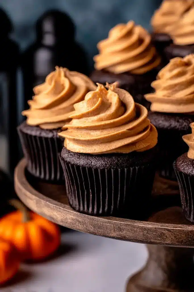 Chocolate Pumpkin Cupcakes | Delicious Cozy Recipe 8 Chocolate Pumpkin Cupcakes on rustic cake stand with smooth pumpkin frosting on white table