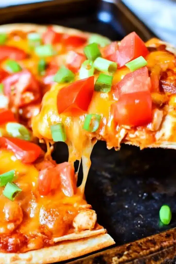 Copycat Taco Bell Mexican Pizzas with gooey melted cheese, tomatoes, and green onions on a crispy tortilla, slice being lifted from whole pizza

