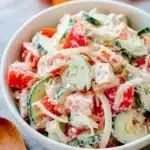 Creamy Cucumber and Tomato Salad | Quick & Refreshing 6 Creamy cucumber and tomato salad with onions in a white bowl, topped with sour cream dressing