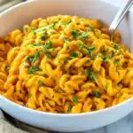 Pumpkin Pasta Sauce tossed with tender noodles and topped with fresh parsley in a white bowl