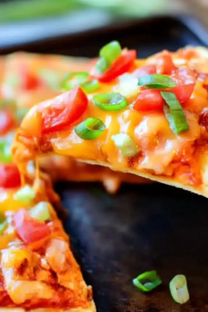 Copycat Taco Bell Mexican Pizzas slice with melted cheese, tomatoes, and green onions on a crispy tortilla being lifted from a whole pizza