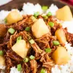 Crockpot Hawaiian BBQ Chicken – Easy, Delicious Slow Cooker 6 Shredded Crockpot Hawaiian BBQ Chicken with pineapple chunks over white rice in a charcoal bowl