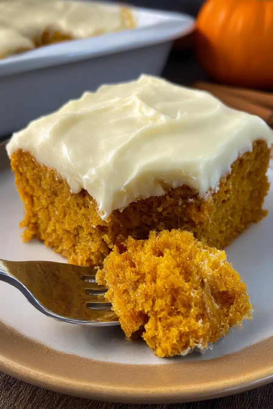 Slice of easy pumpkin carrot cake with cream cheese frosting and fork on plate