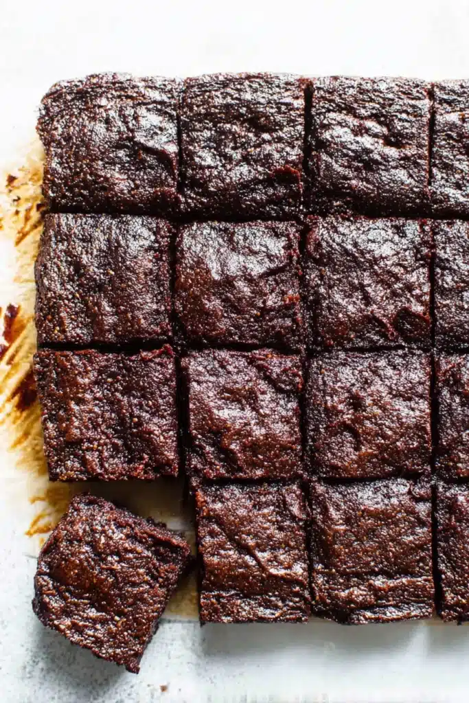 Zucchini Brownies – Fudgy, Healthy, Irresistible 11 Pan of sliced zucchini brownies with glossy tops on parchment paper