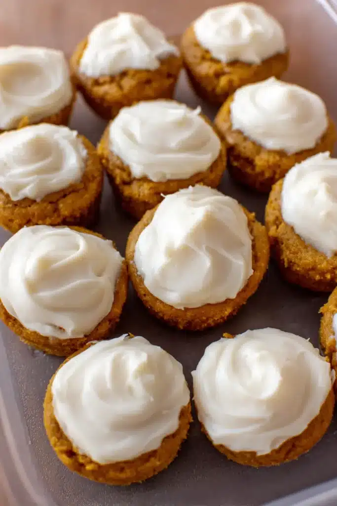 Flourless Pumpkin Muffins 6 Close-up of frosted mini pumpkin muffins arranged in a plastic container.