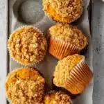 Pumpkin Oatmeal Muffins (Soft, Spiced & Easy) 6 Pumpkin oatmeal muffins with crisp oat streusel in a parchment-lined tray on a light surface