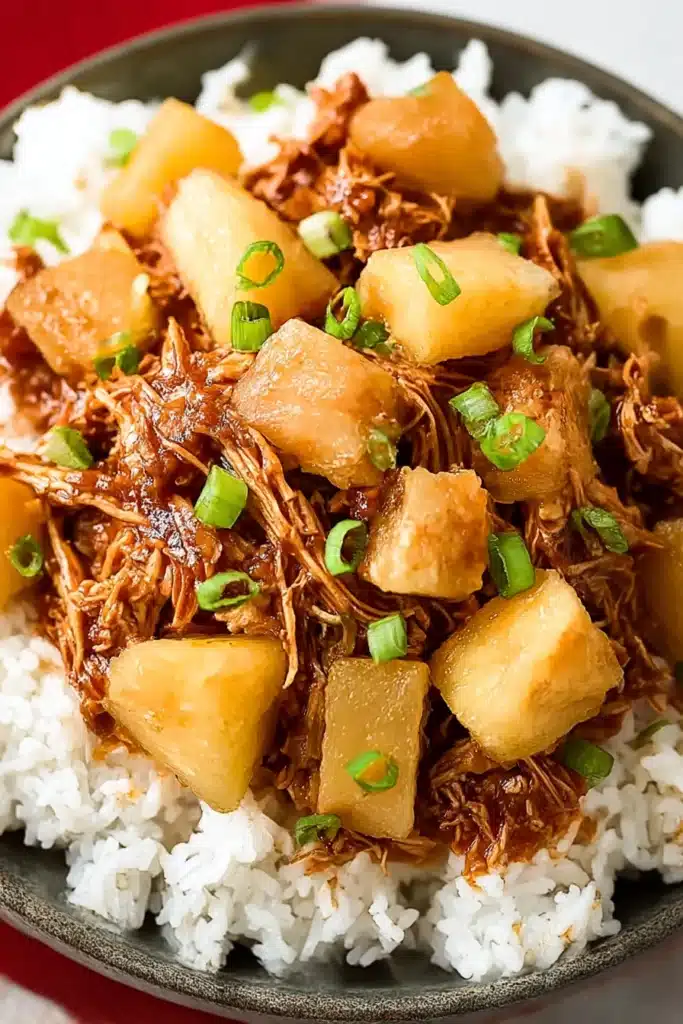 Top-down view of Hawaiian BBQ chicken with pineapple and scallions over white rice in a charcoal bowl